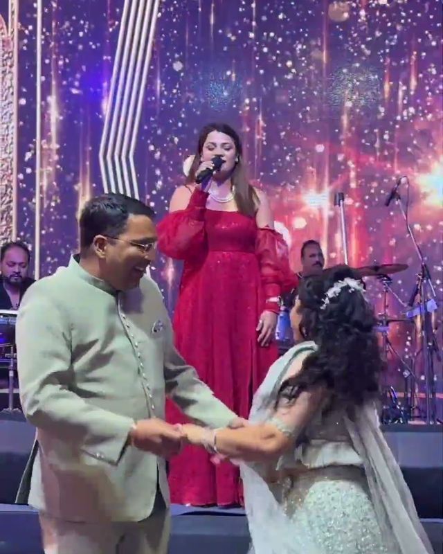 Paaridhi Sharma singing on stage as a couple dances at a sangeet