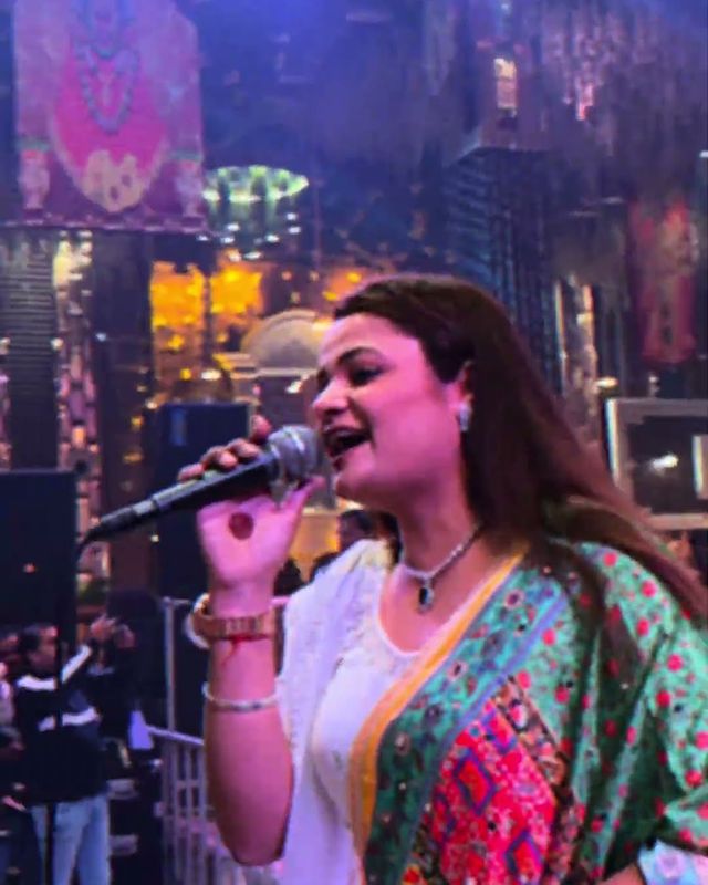 Paaridhi Sharma singing into a handheld mic under stage lights