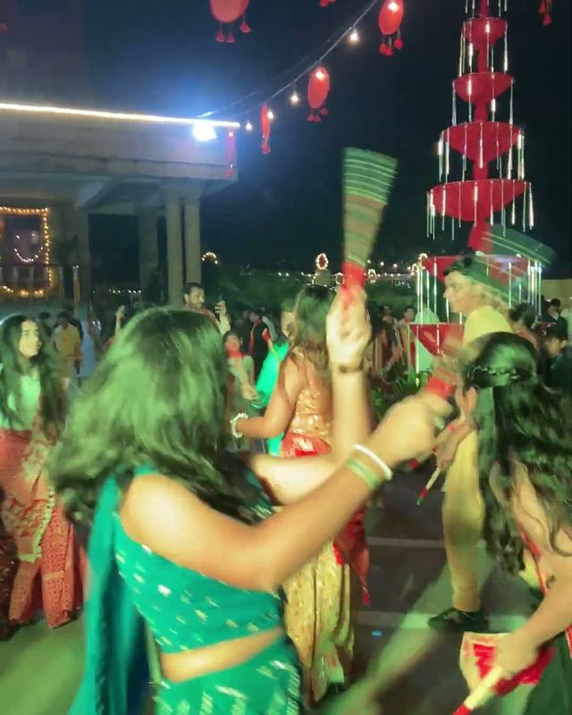 Guests playing dandiya under a lit garba tower