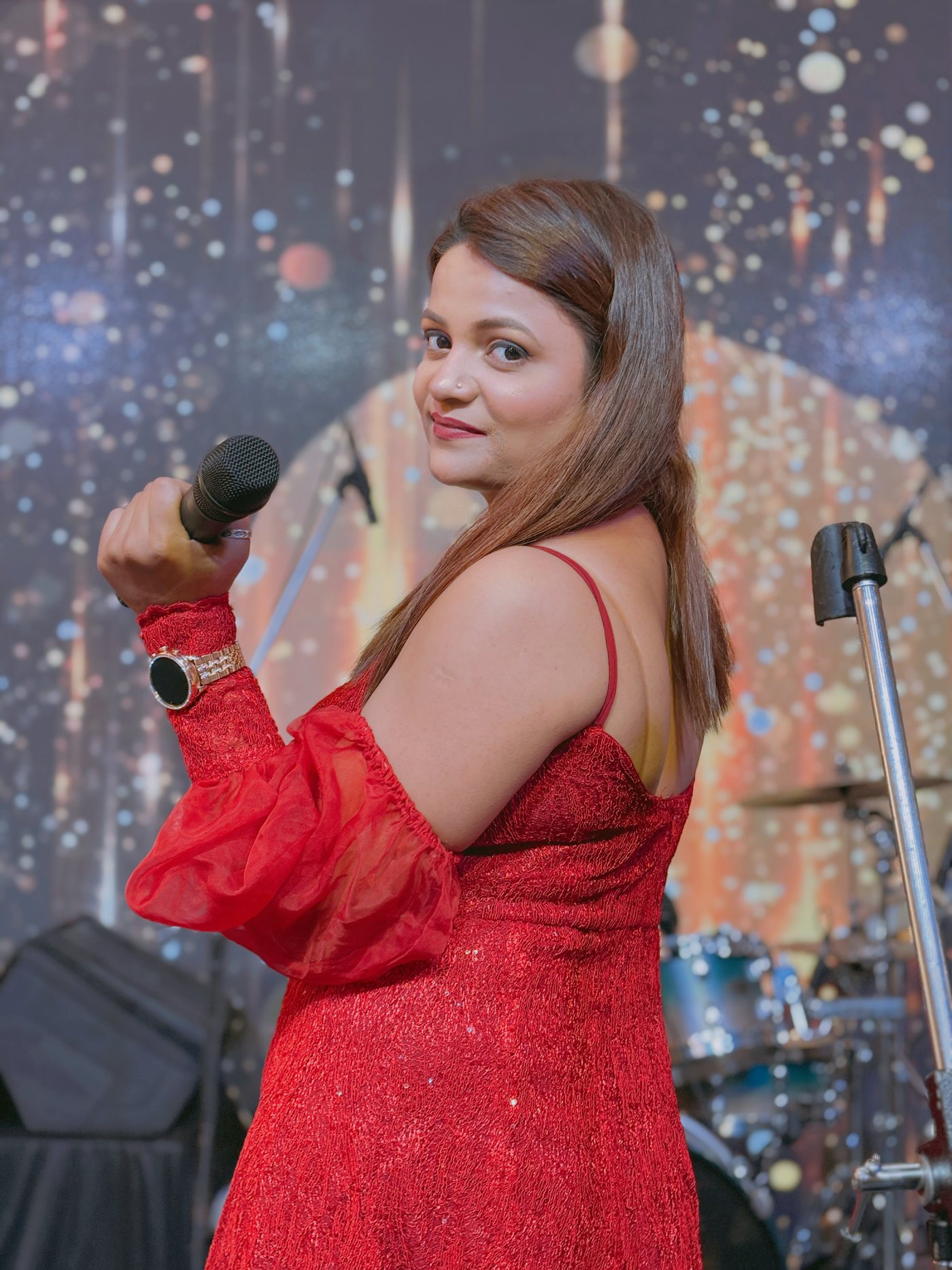 Paaridhi Sharma singing on stage in a red dress